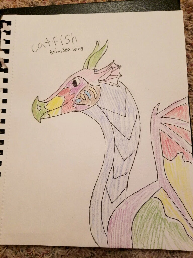 A drawing on paper of Catfish from the shoulder up. His wings are green, yellow, and red like his snout.